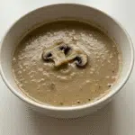 Creamy Mushroom Soup 6 A bowl of creamy mushroom soup garnished with fresh parsley and served with crusty bread